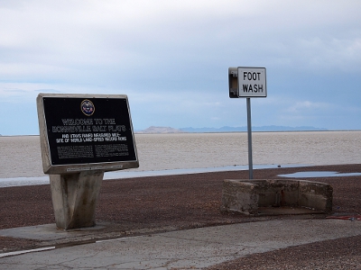 [Foot Wash sign over a basin area near the edge of the salty ground. Beside it is a Welcome to the Bonneville Salt Flats sign.]